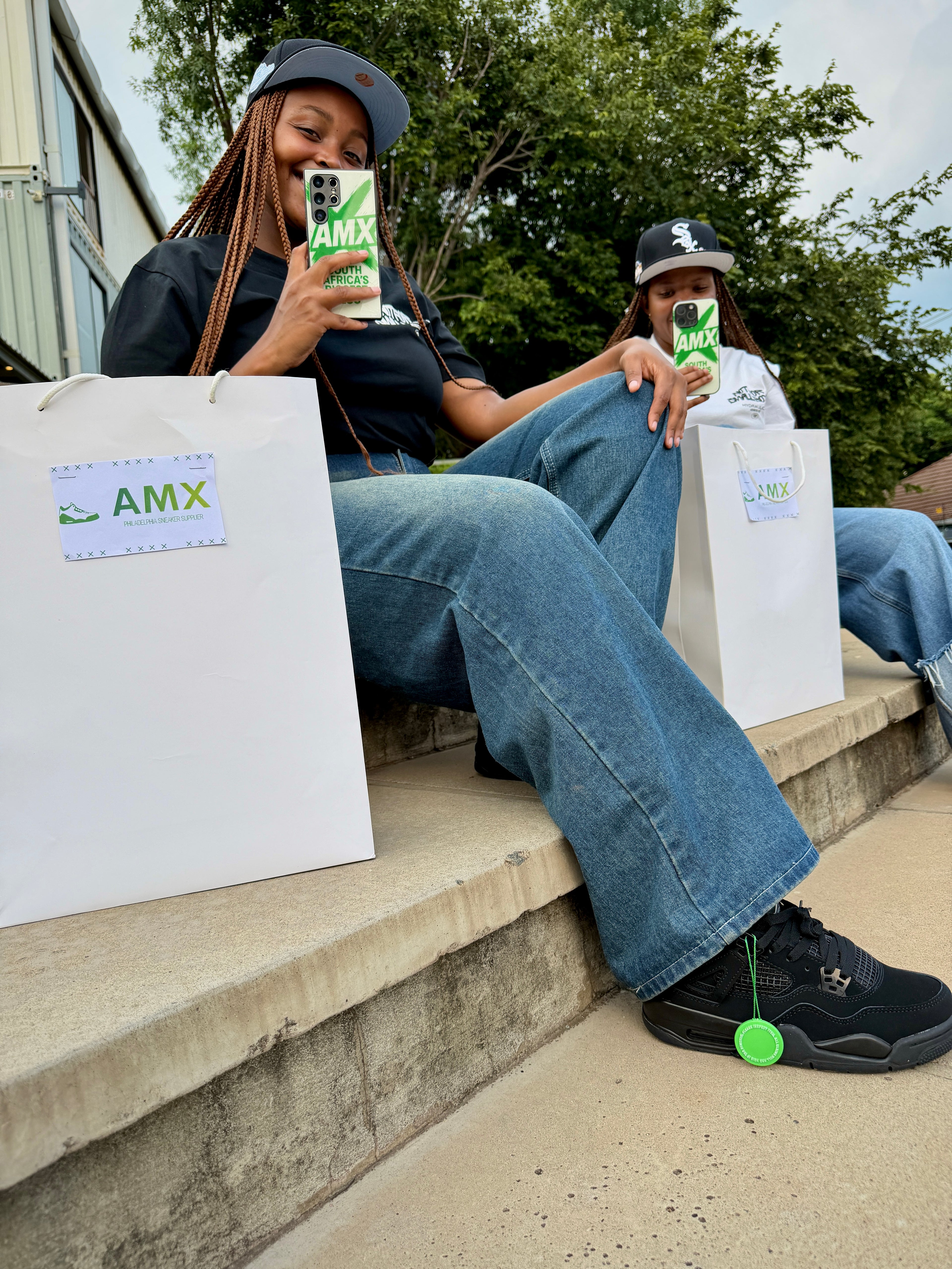 Two people sitting on steps holding AMX products and bags.